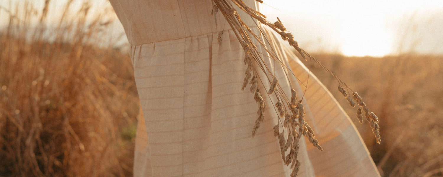 Close up image of a handwoven dress with a bundle of dry grass